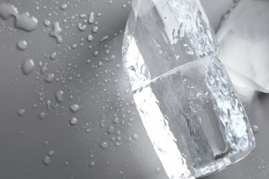 Photo of Pieces of clear ice and water drops on light grey table, top view. Space for text