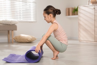 Cute little girl with fitness mat at home