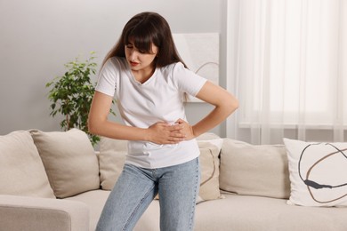 Upset woman suffering from abdominal pain at home