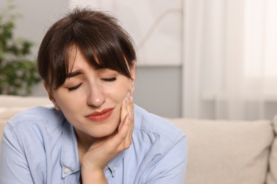 Photo of Upset young woman suffering from toothache indoors, space for text