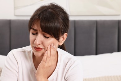 Photo of Upset young woman suffering from toothache indoors