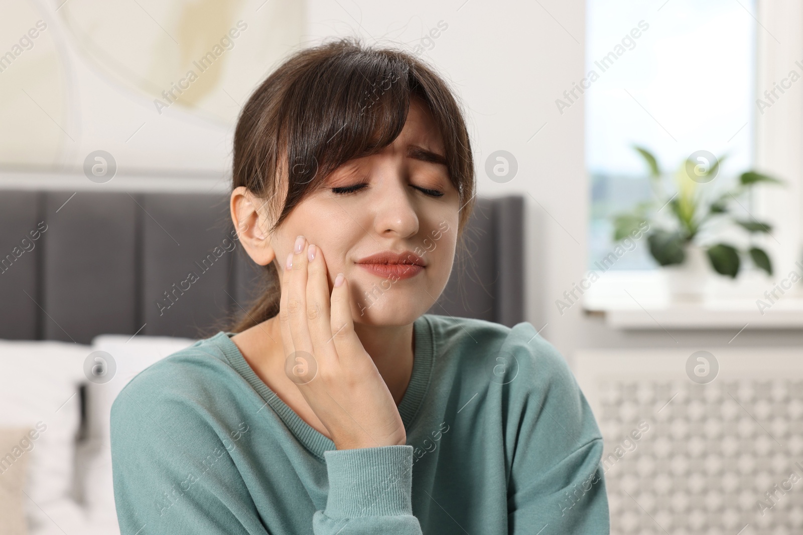 Photo of Upset young woman suffering from toothache indoors