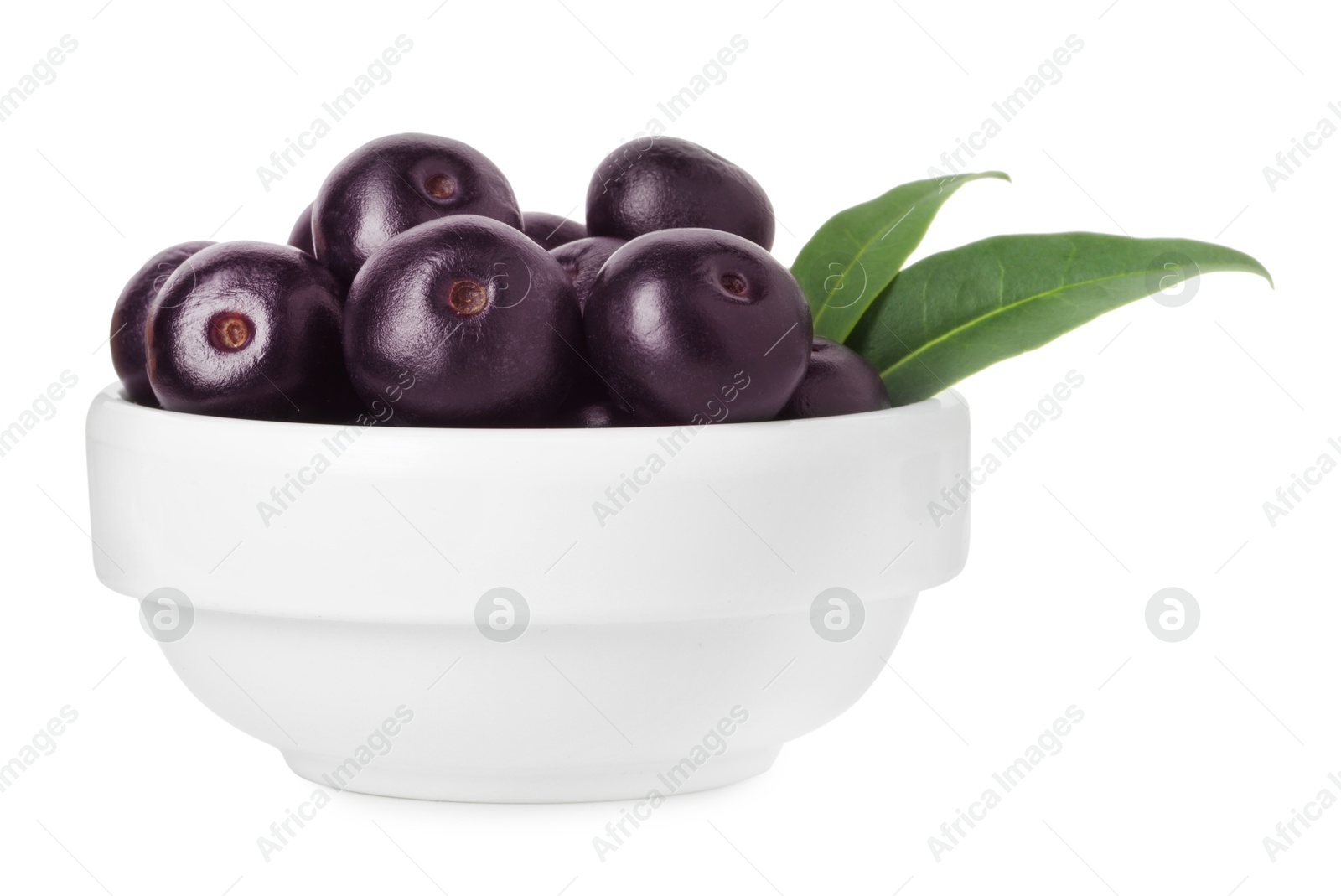 Photo of Fresh ripe acai berries in bowl and green leaves isolated on white