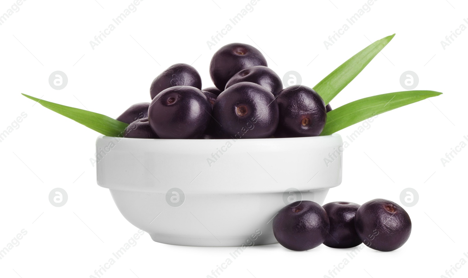 Photo of Fresh ripe acai berries in bowl and green leaves isolated on white