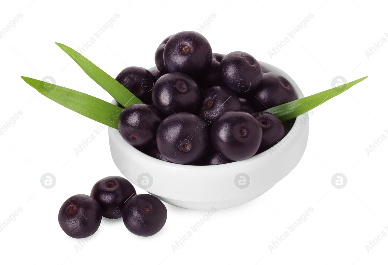 Photo of Fresh ripe acai berries in bowl and green leaves isolated on white