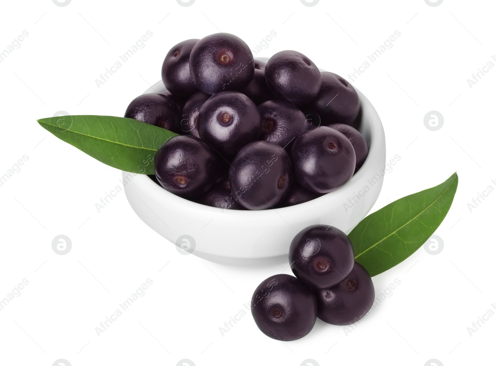 Photo of Fresh ripe acai berries in bowl and green leaves isolated on white