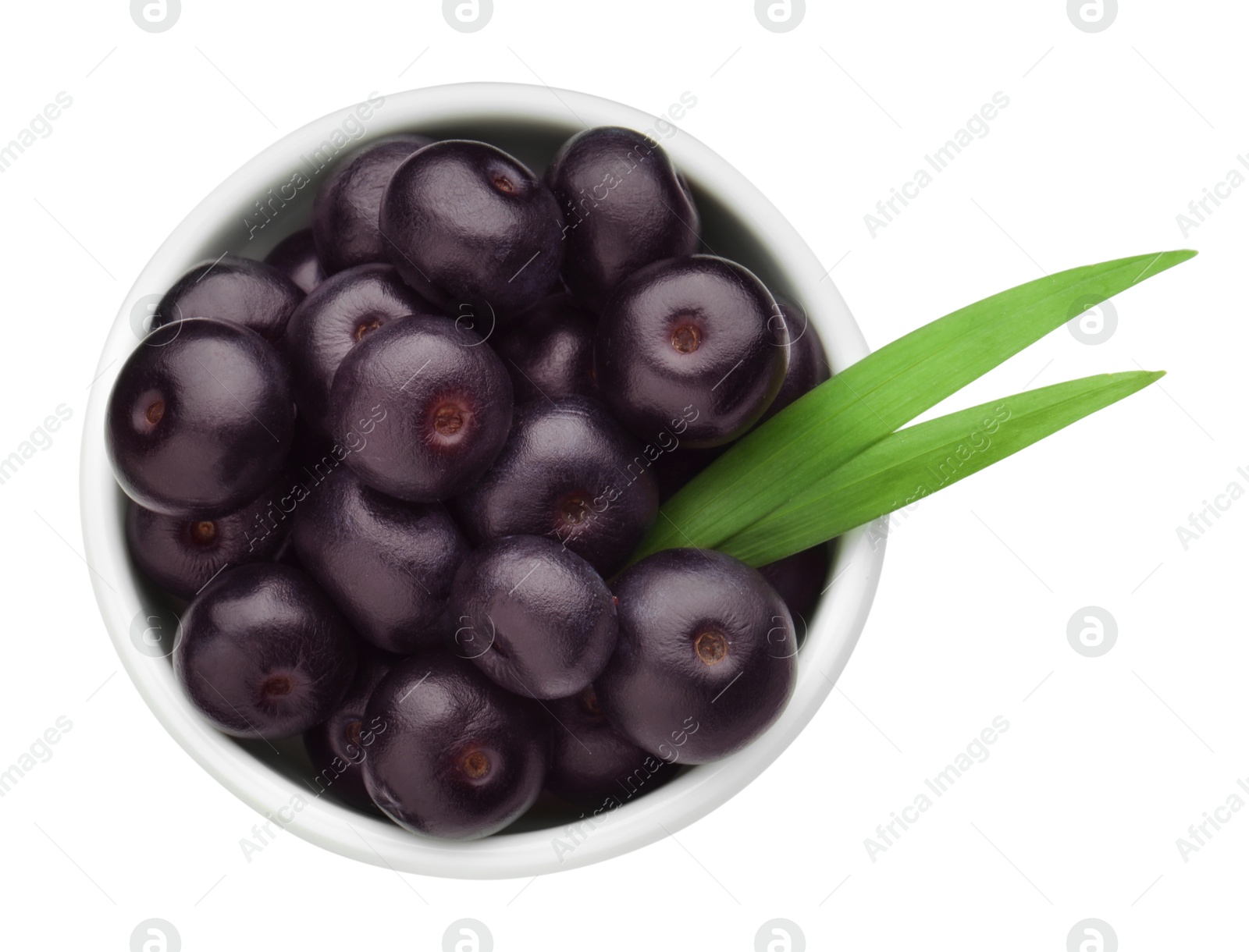 Photo of Fresh ripe acai berries in bowl and green leaves isolated on white, top view