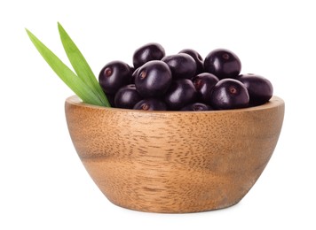 Fresh ripe acai berries in bowl and green leaves isolated on white