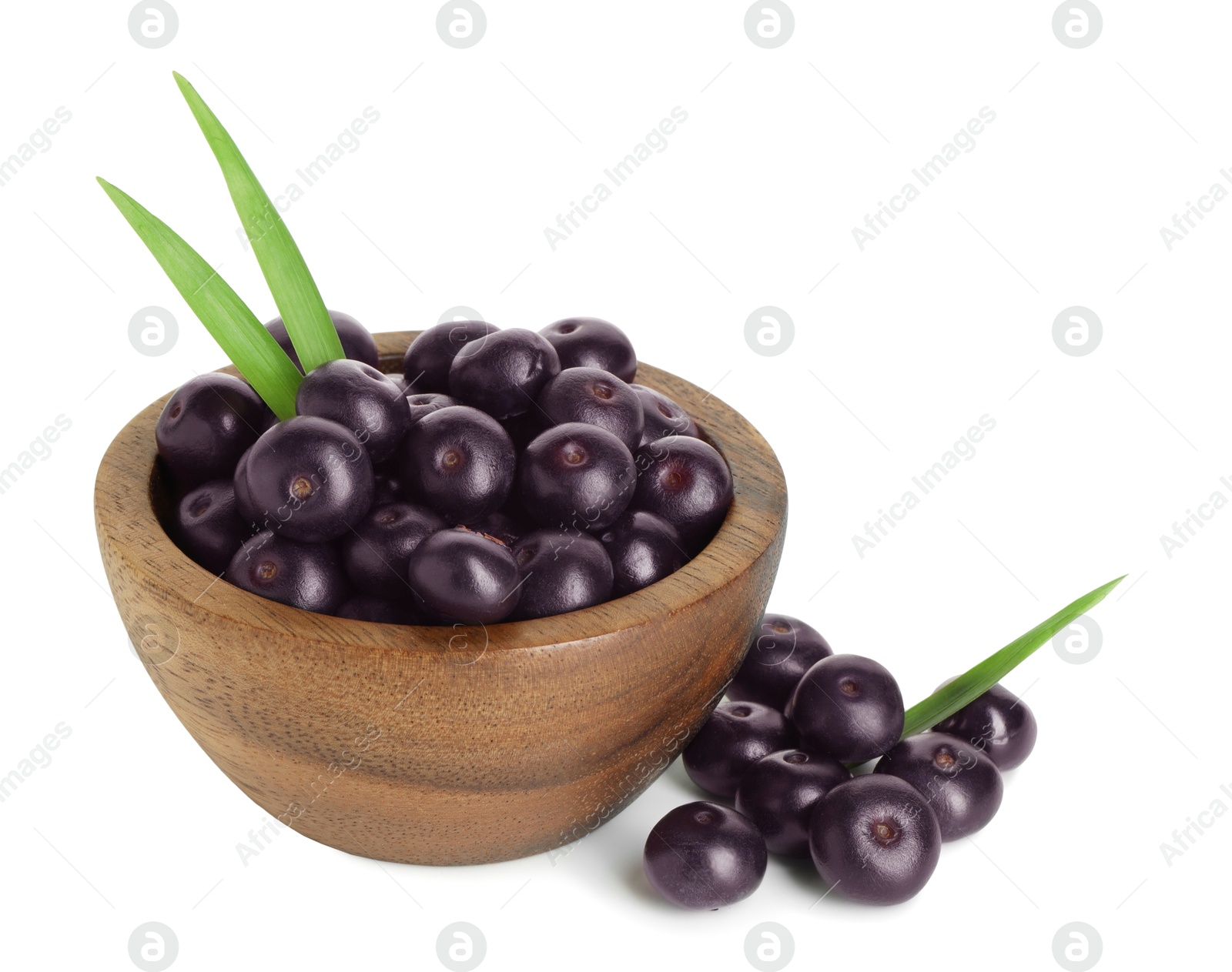 Photo of Fresh ripe acai berries in bowl and green leaves isolated on white