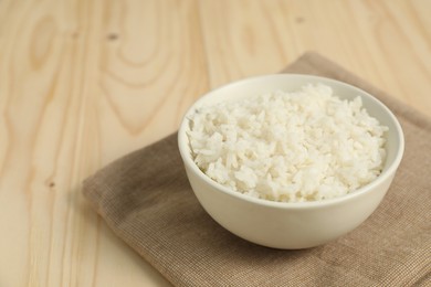 Photo of Delicious boiled rice in bowl on wooden table