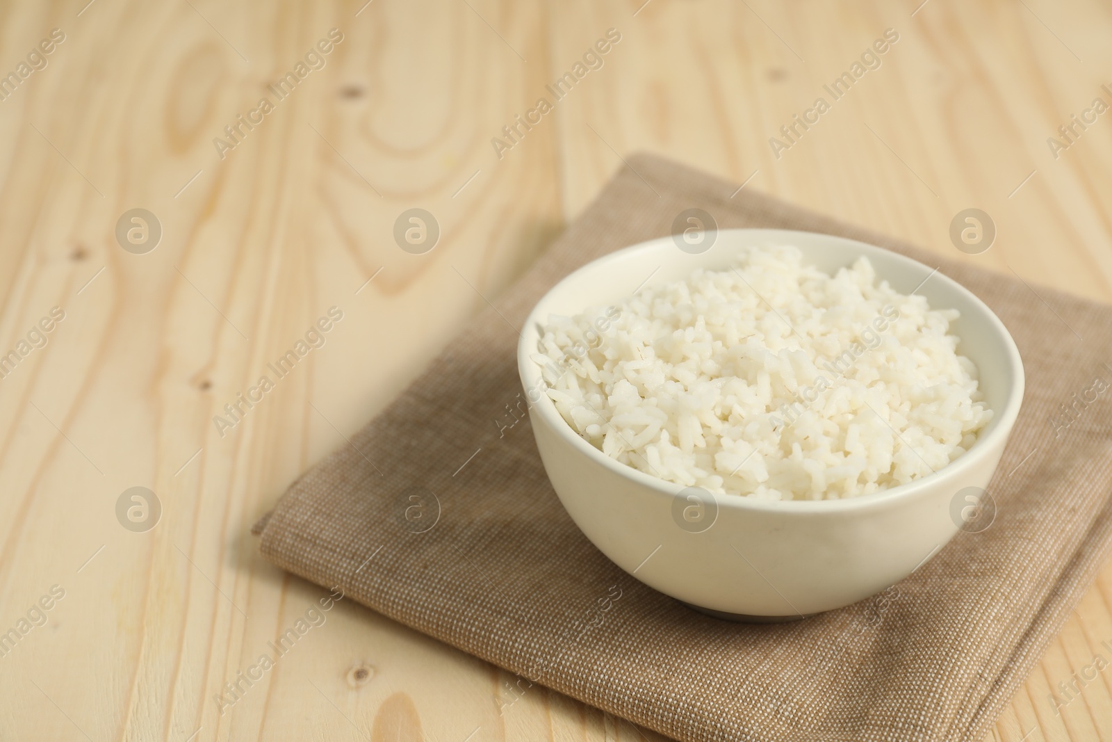 Photo of Delicious boiled rice in bowl on wooden table