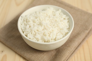 Photo of Delicious boiled rice in bowl on wooden table, closeup