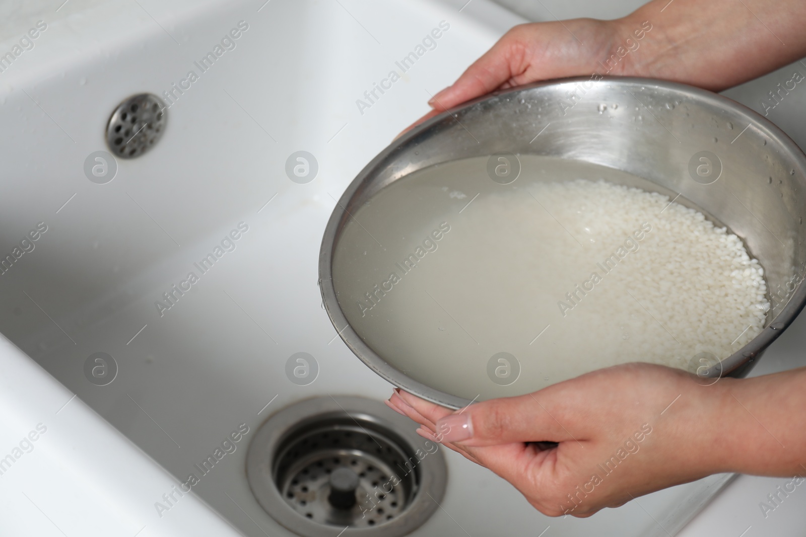 Photo of Woman rinsing rice in bowl above sink, closeup. Space for text