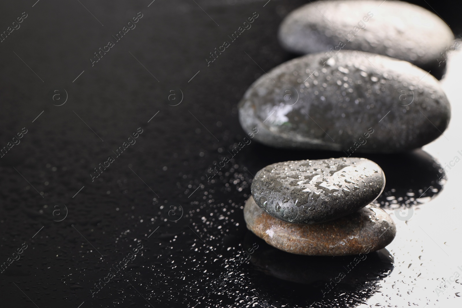 Photo of Grey spa stones with water drops on black background, closeup. Space for text