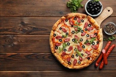 Photo of Tasty pizza and ingredients on wooden table, top view. Space for text