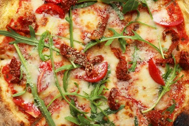 Photo of Tasty pizza with cheese, tomato and arugula as background, top view