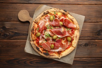 Photo of Tasty pizza with cured ham, olives and sun-dried tomato on wooden table, top view