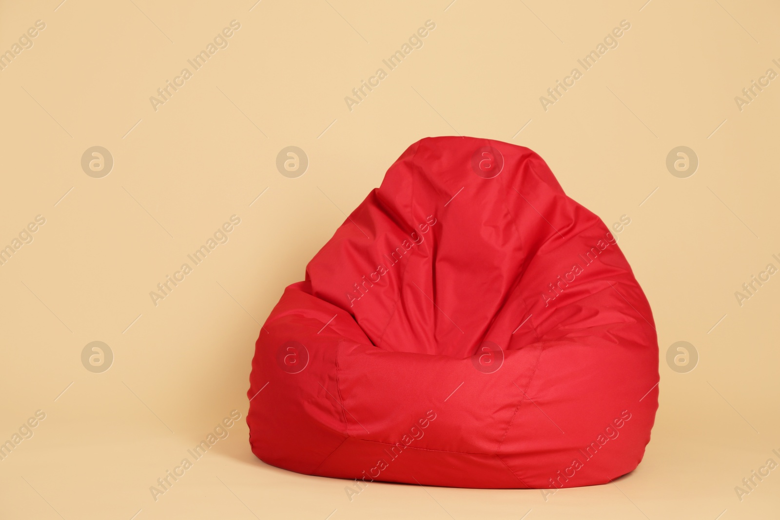 Photo of Red bean bag chair on beige background, space for text