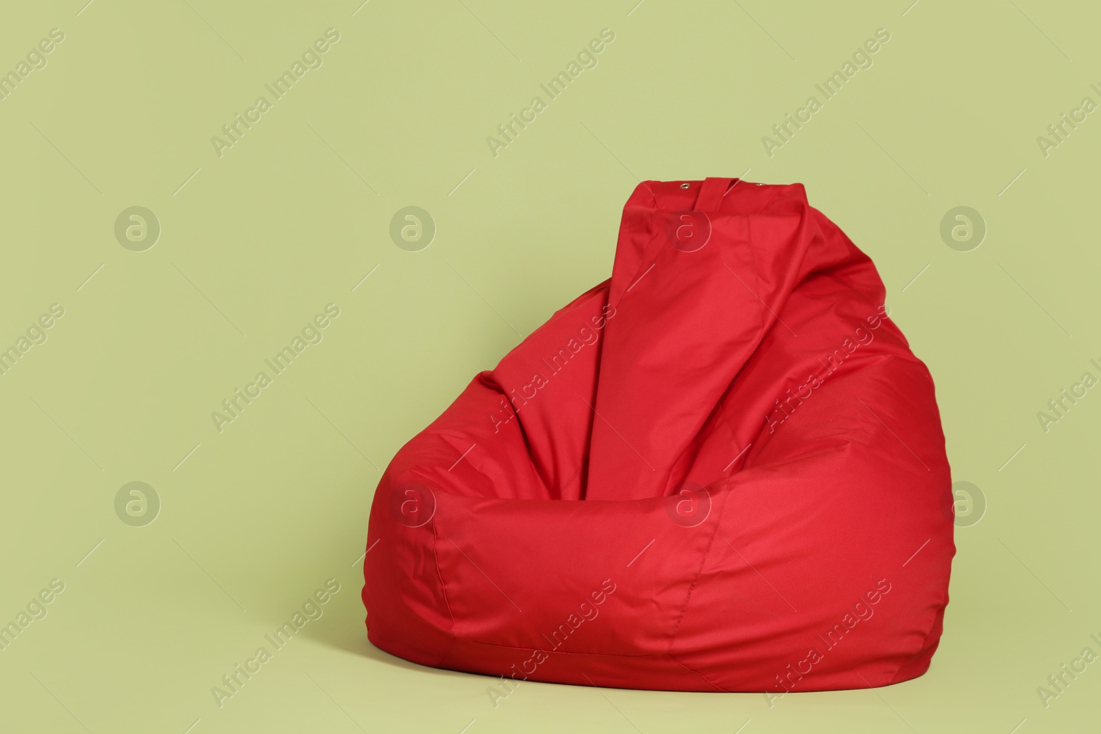 Photo of Red bean bag chair on olive background, space for text