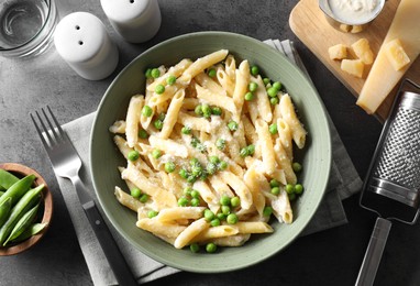 Photo of Delicious pasta with green peas served on grey table, top view