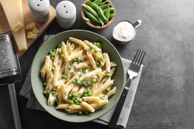 Photo of Delicious pasta with green peas served on grey table, top view