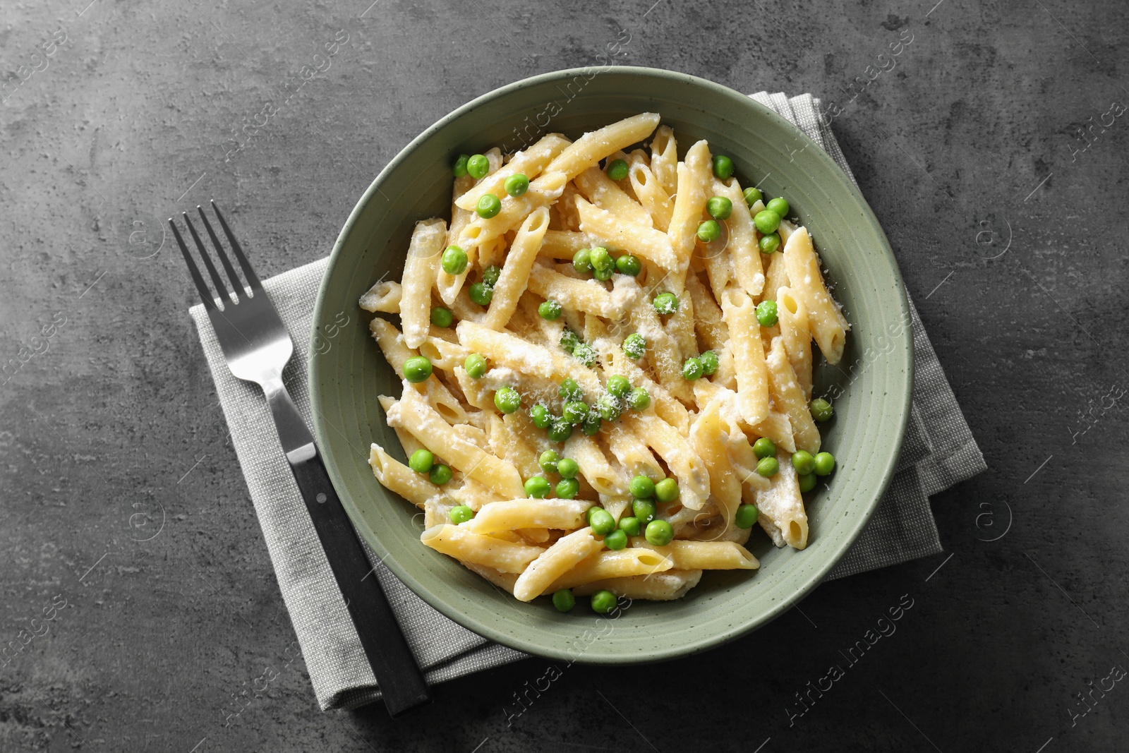 Photo of Delicious pasta with green peas, cheese and fork on grey table, top view