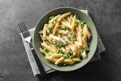 Photo of Delicious pasta with green peas, cheese and fork on grey table, top view