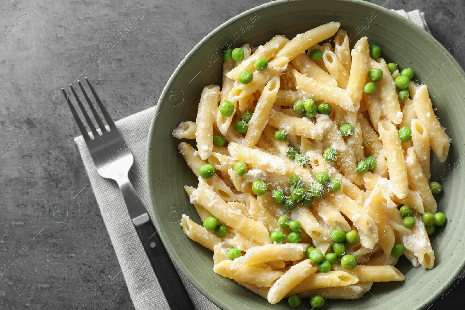 Photo of Delicious pasta with green peas, cheese and fork on grey table, top view