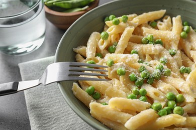 Photo of Delicious pasta with green peas served on grey table, closeup