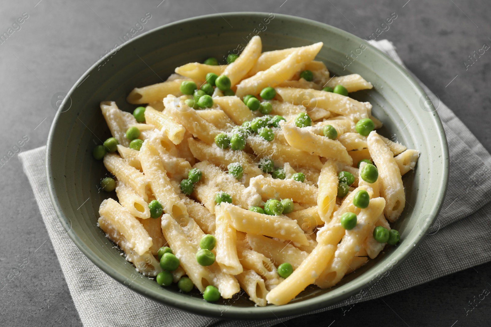 Photo of Delicious pasta with green peas and cheese on grey table