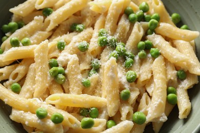 Photo of Delicious pasta with green peas and cheese in bowl, closeup