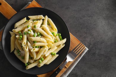 Photo of Delicious pasta with green peas, cheese and fork on grey table, top view. Space for text