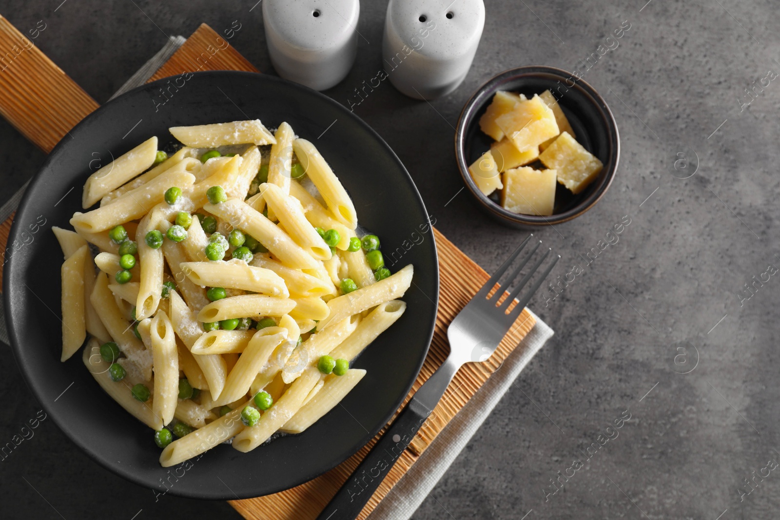 Photo of Delicious pasta with green peas, cheese and fork on grey table, top view. Space for text