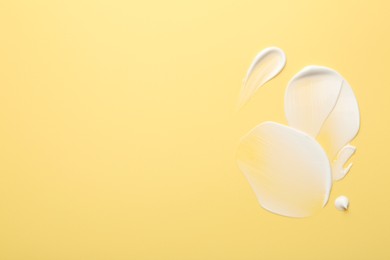 Samples of face cream on yellow background, top view. Space for text