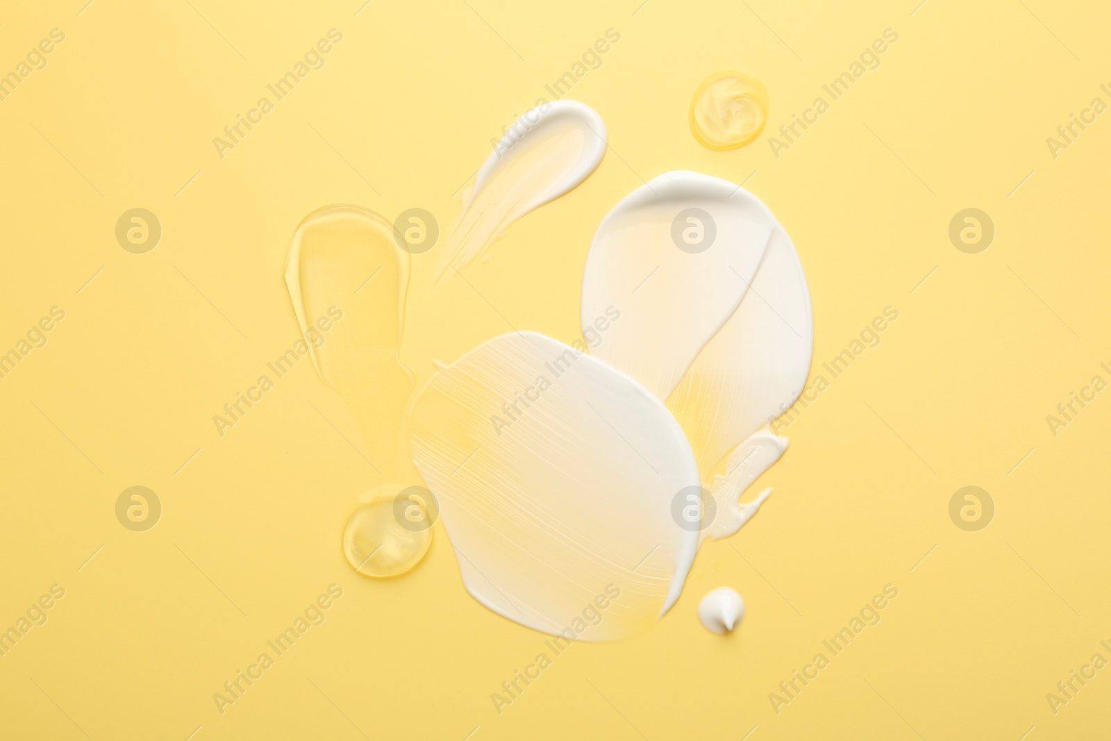 Photo of Samples of face cream on yellow background, top view