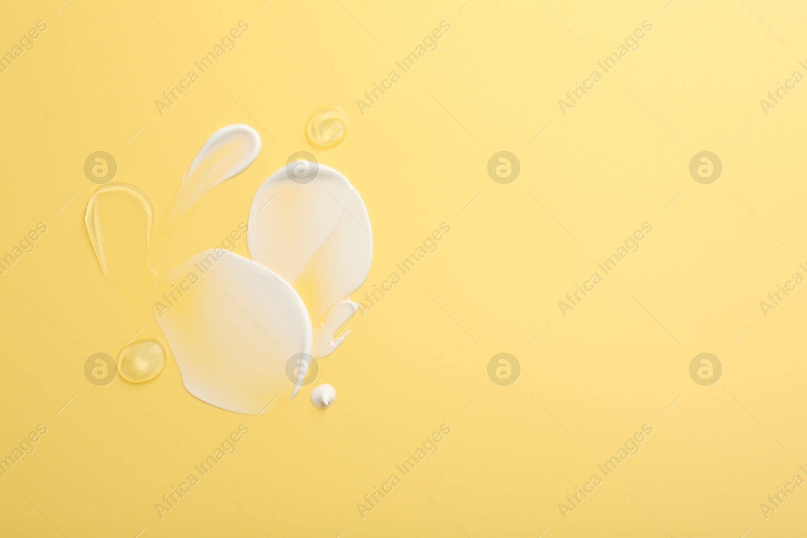 Photo of Samples of face cream on yellow background, top view. Space for text