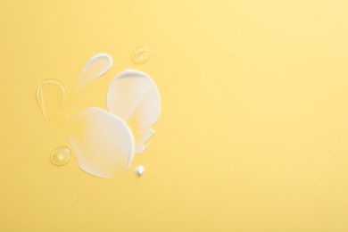 Samples of face cream on yellow background, top view. Space for text