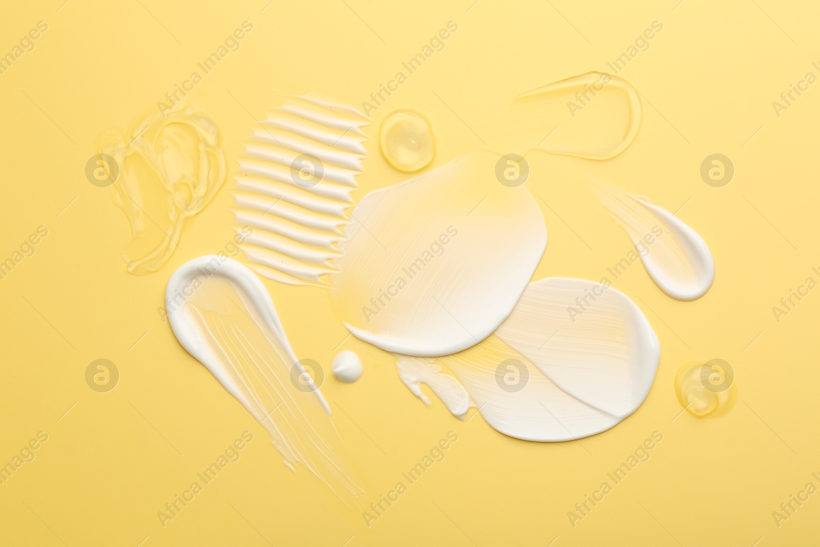 Photo of Samples of face cream on yellow background, top view