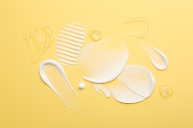 Photo of Samples of face cream on yellow background, top view