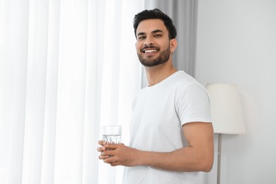 Photo of Happy man with glass of water at morning. Space for text