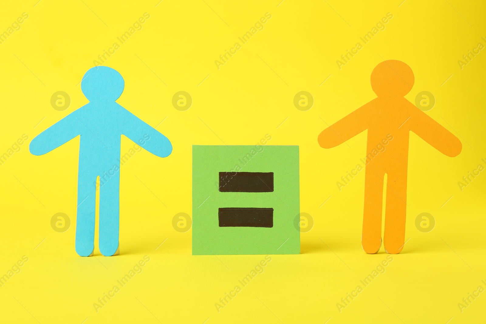 Photo of Paper human figures of different colors and equal sign on yellow background