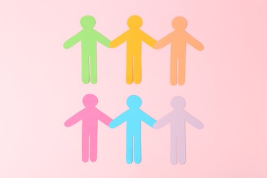 Photo of Equality concept. Paper human figures of different colors on pink background, top view