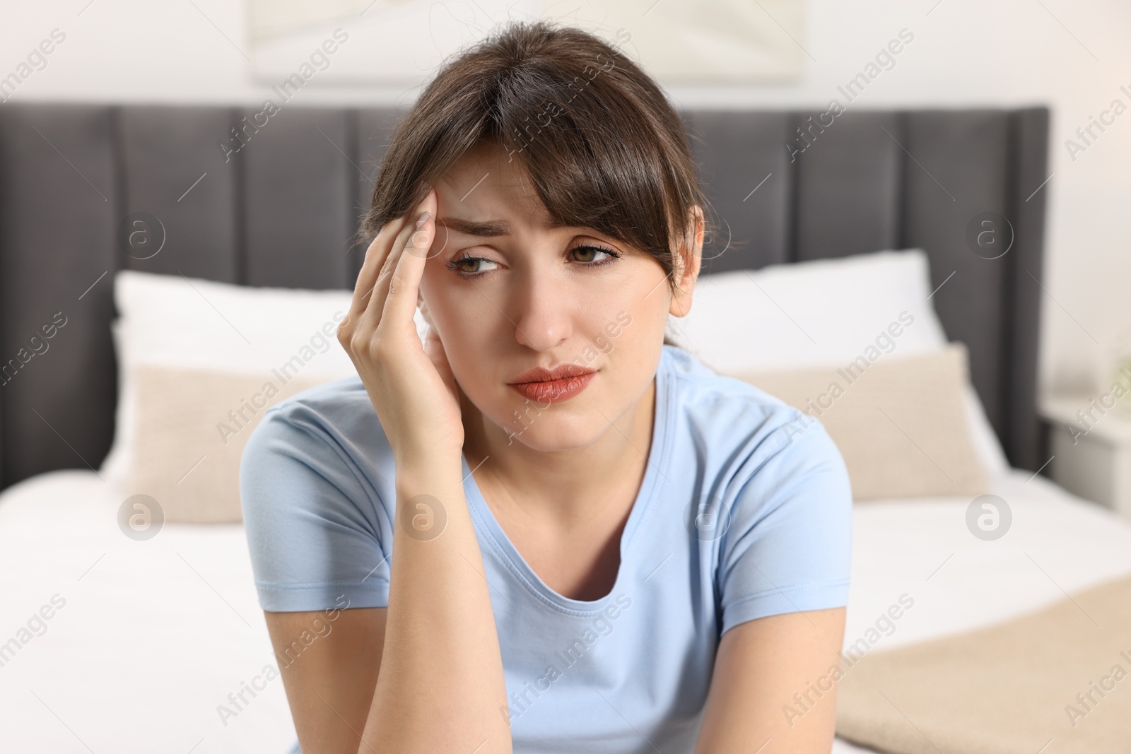 Photo of Upset young woman suffering from headache indoors