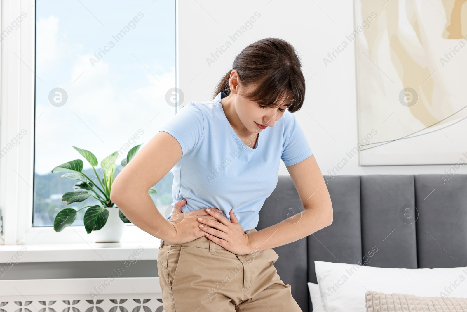 Photo of Young woman suffering from abdominal pain at home