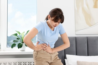 Young woman suffering from abdominal pain at home