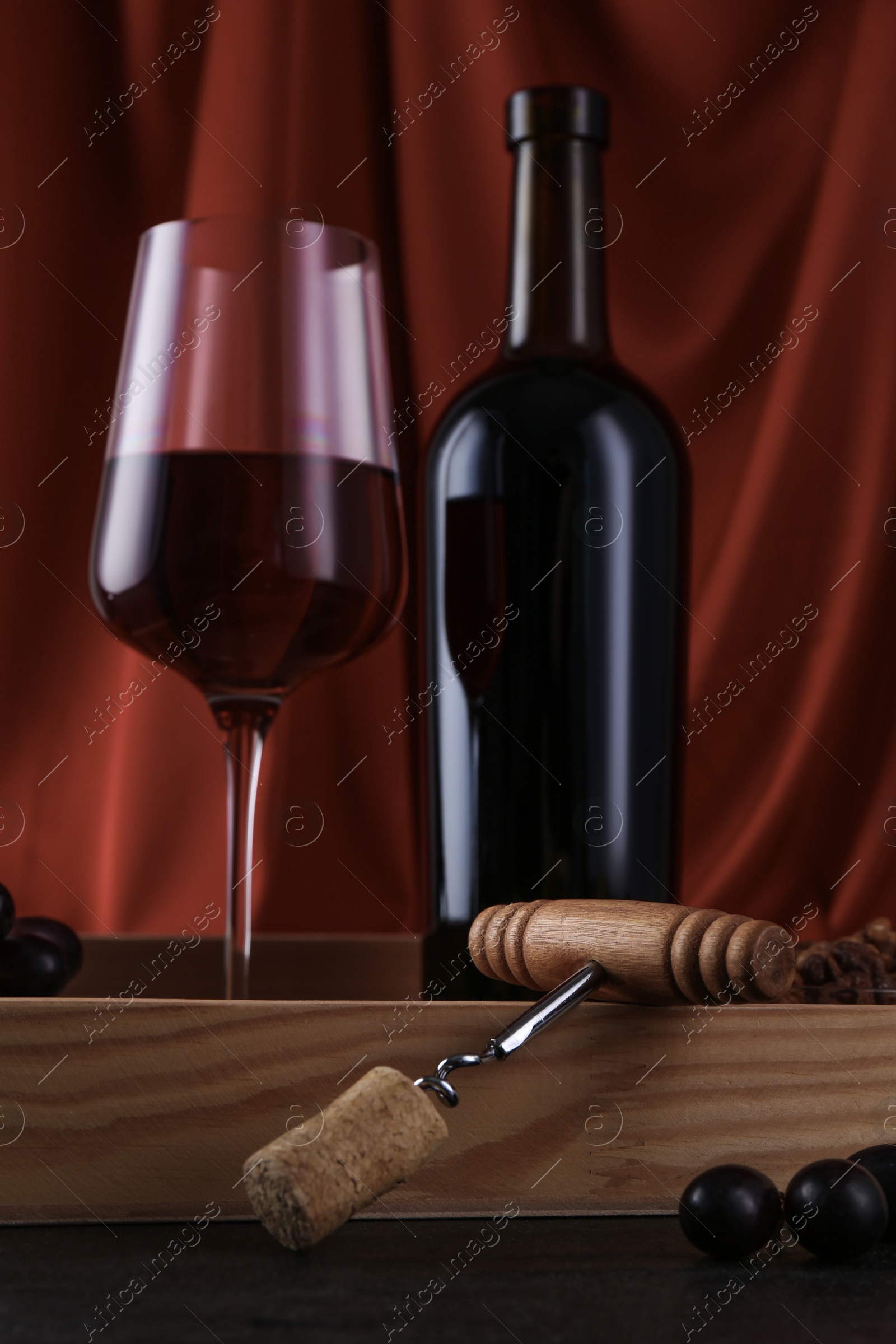 Photo of Corkscrew, glass of wine, bottle and grapes on table