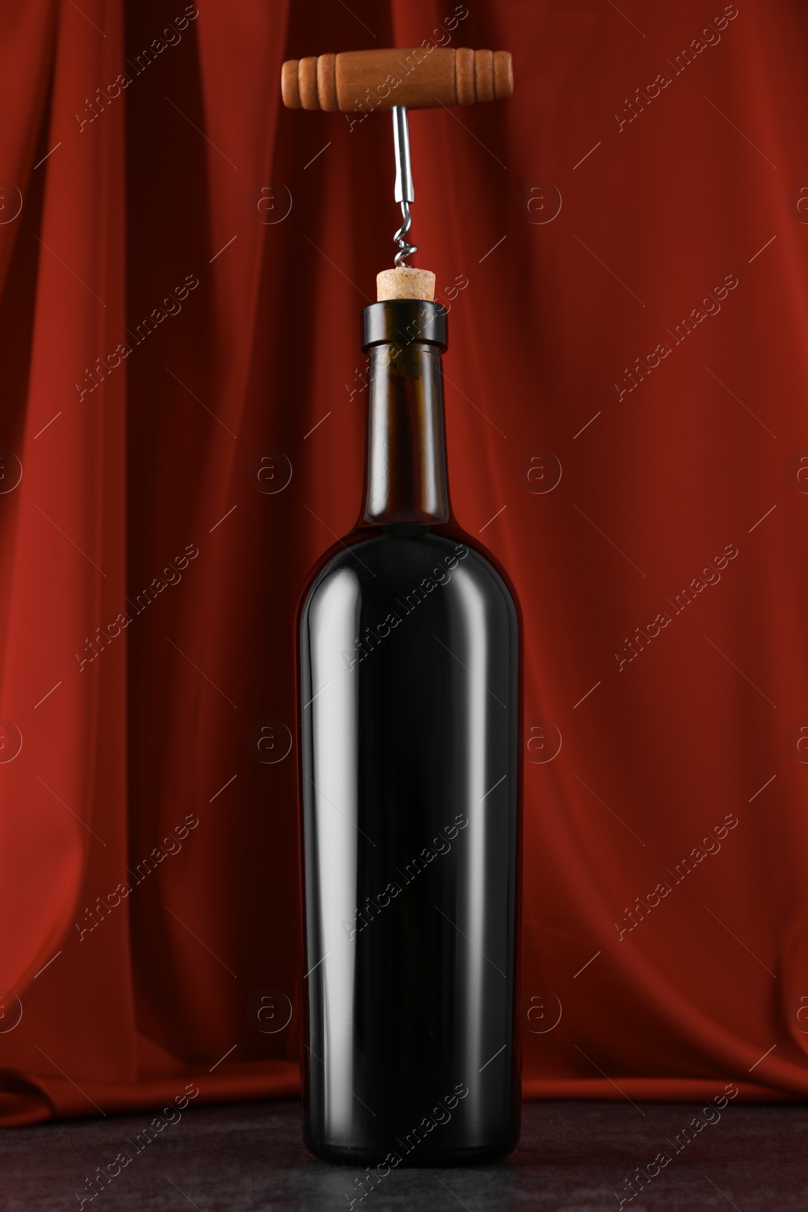 Photo of Corkscrew and bottle of wine on black table