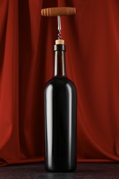 Corkscrew and bottle of wine on black table