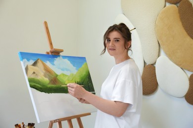 Photo of Woman drawing landscape with brush in studio