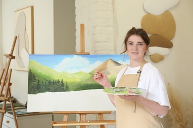 Portrait of smiling woman drawing landscape with brush in studio